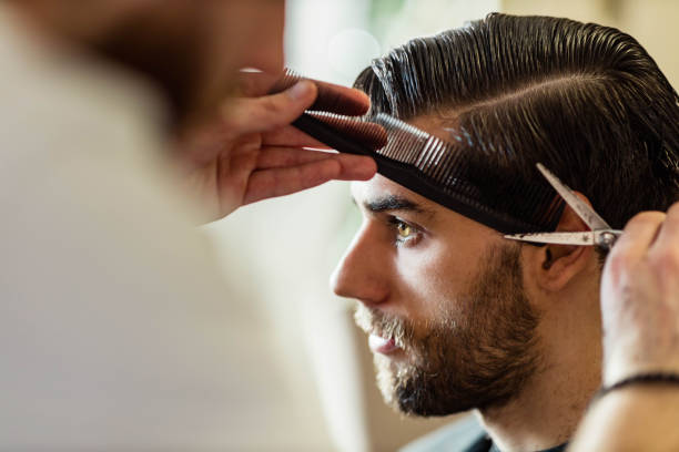 Young man having his hair styled by a barber at home. Copy space